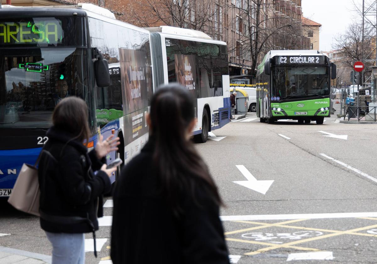 Dos jóvenes se disponen a cruzar la calle en la zona de Santa Clara a la espera de que pasen los autobuses.