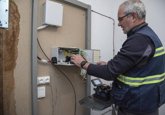 Un trabajador instala un aparato para mejorar la señal de televisión en un edificio.