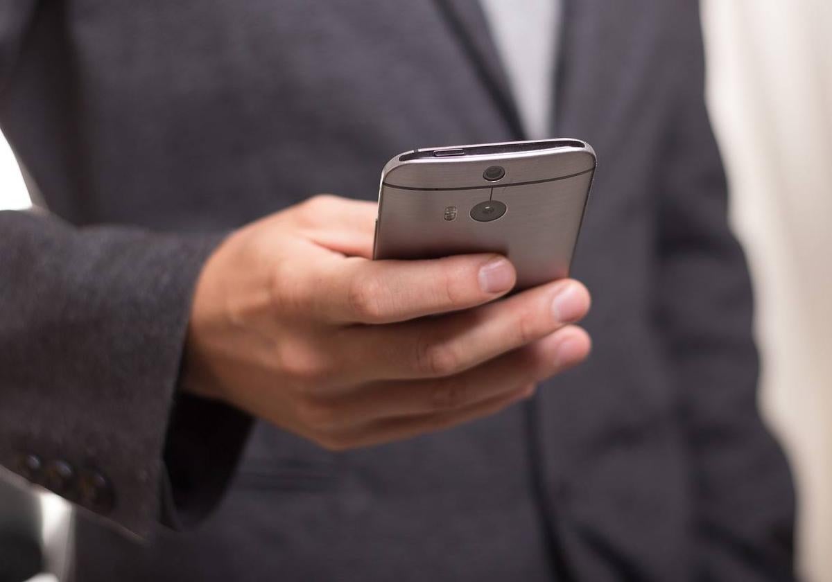 Un hombre sostiene un teléfono móvil.