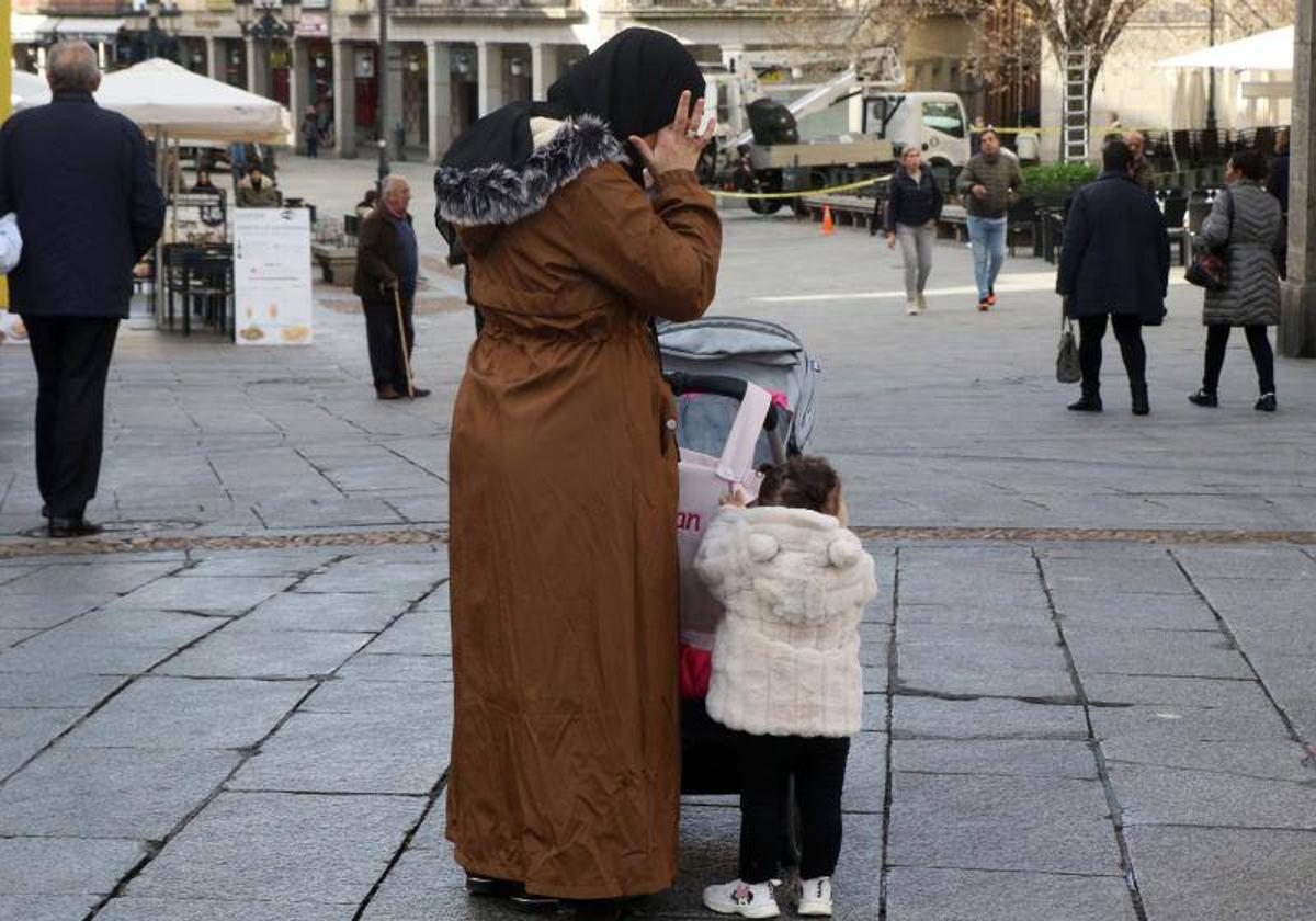 Una mujer empuja un carrito junto a una niña en Segovia.