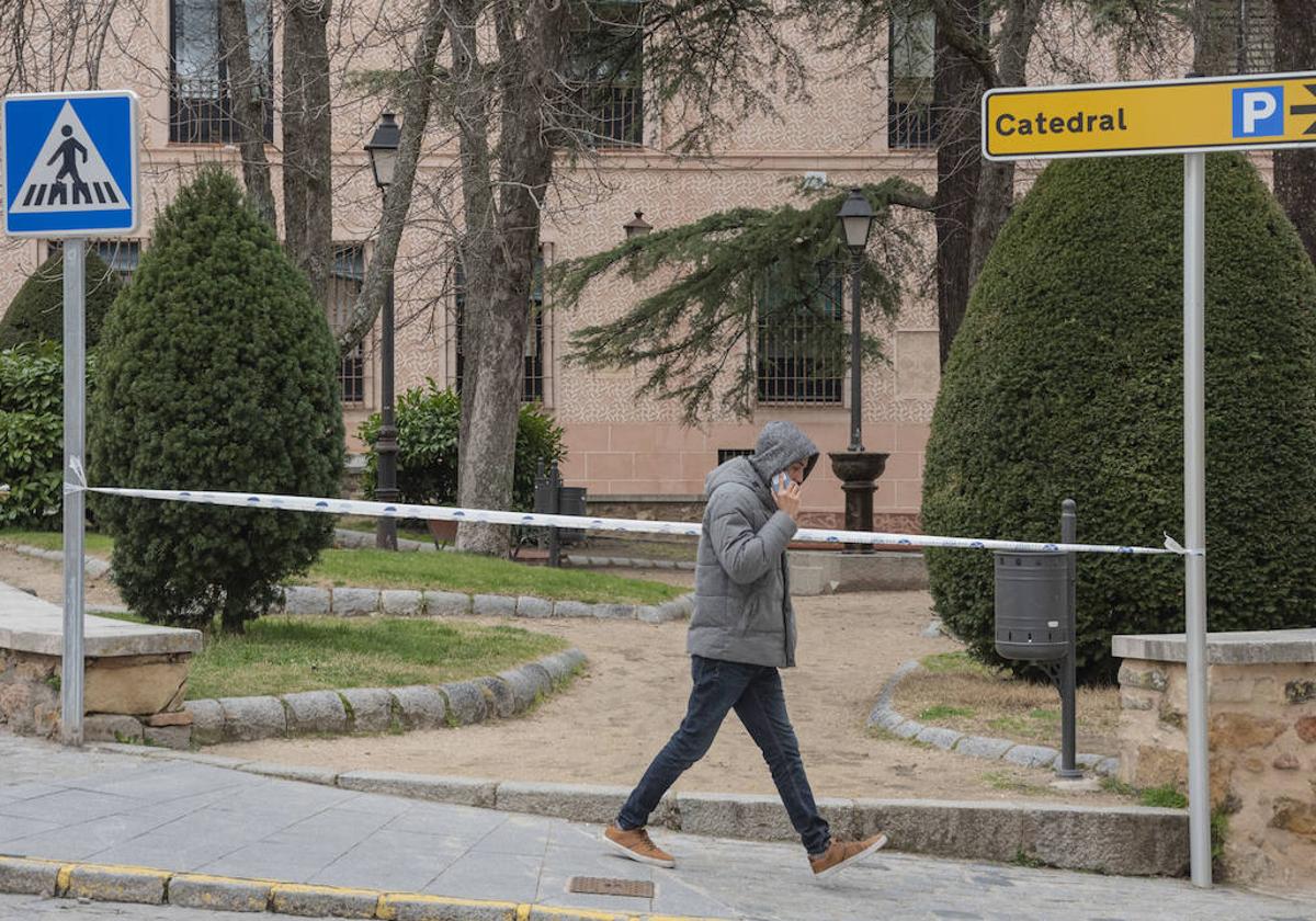 Un joven pasea junto a uno de los espacios verdes cerrados por el fuerte viento en Segovia este domingo.