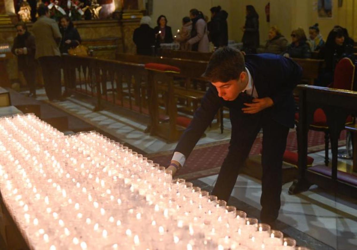 Un joven enciende una vela junto al altar de la iglesia de Jesús.