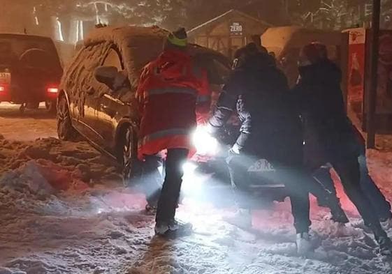 Varias personas empujan un vehículo para rescatarlo al quedar atrapado por la nevada el sábado pasado en La Pinilla.