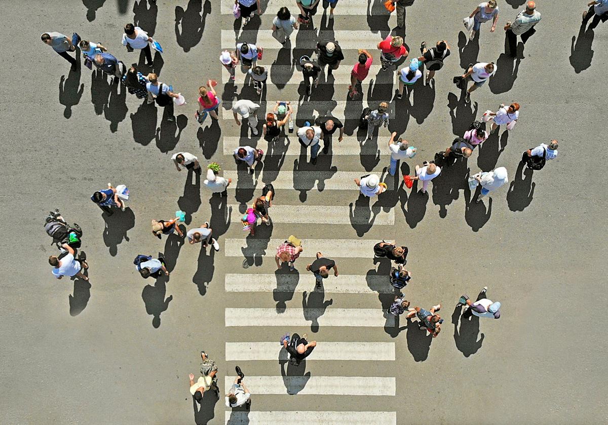 Varias personas atraviesan un paso de peatones.