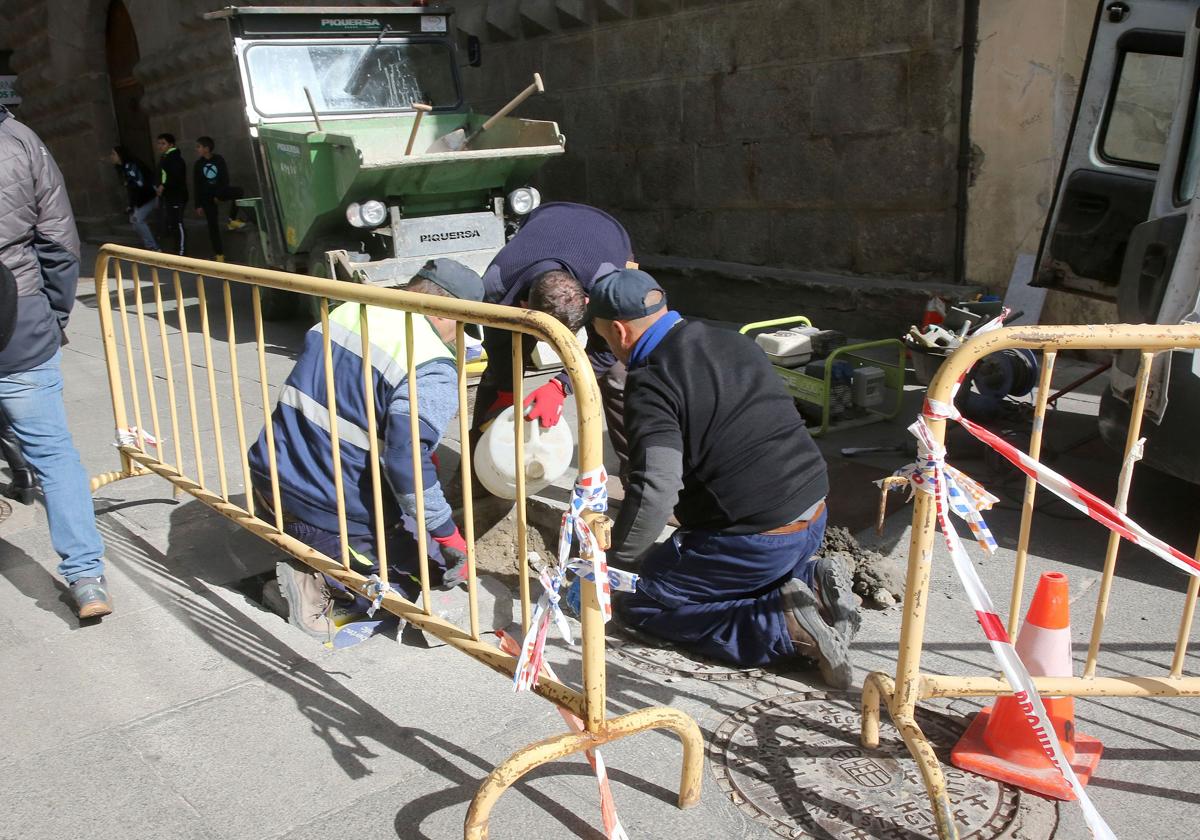 Unos operarios arreglan unas baldosas en la Calle Real de Segovia esta semana.