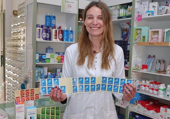 Ana Deza muestra las pegatinas identificativas para medicamentos infantiles en la farmacia de Ampudia.