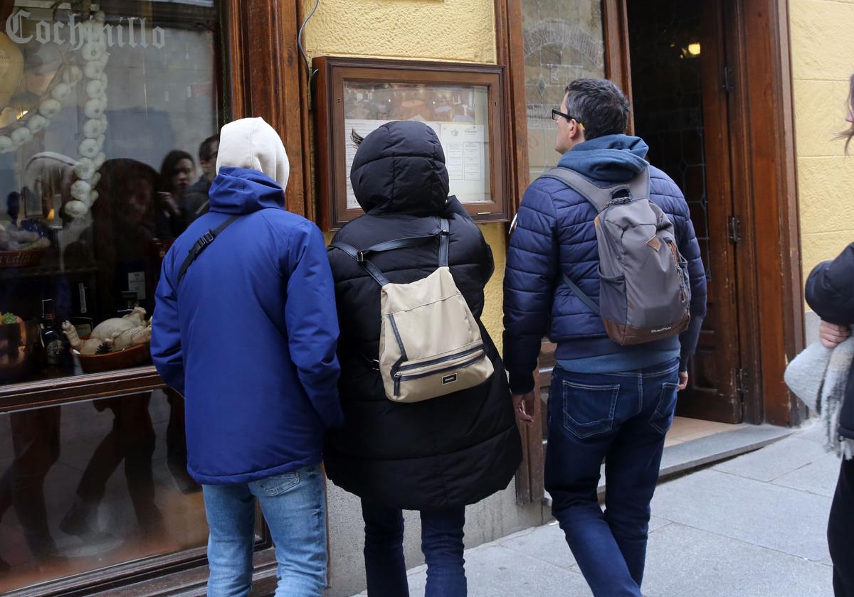 Un grupo de turistas revisa la carta de un restaurante de la ciudad de Segovia.