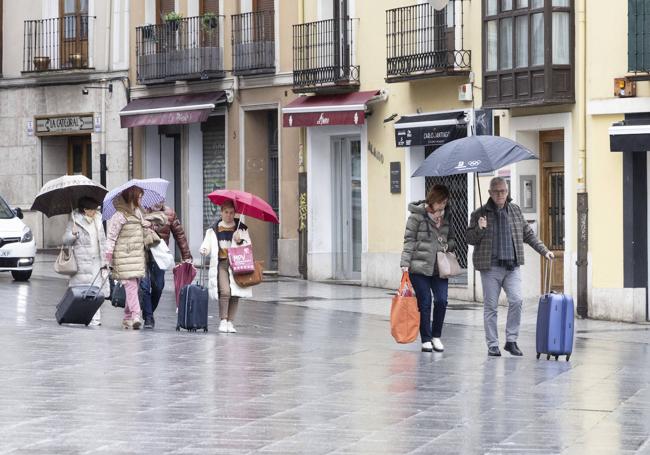 Los turistas abandonan el centro de la ciudad con paraguas este Domingo de Resurrección.