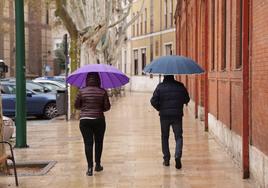 Dos viandantes se protegen de la lluvia en la mañana del domingo.