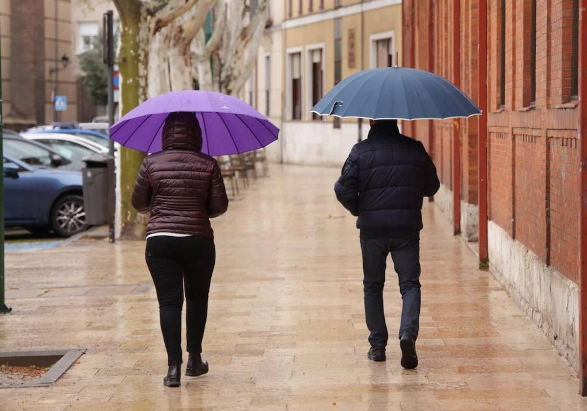 Dos viandantes se protegen de la lluvia en la mañana del domingo.