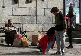 Varias personas esperan con maletas en el centro de la ciudad de Segovia.
