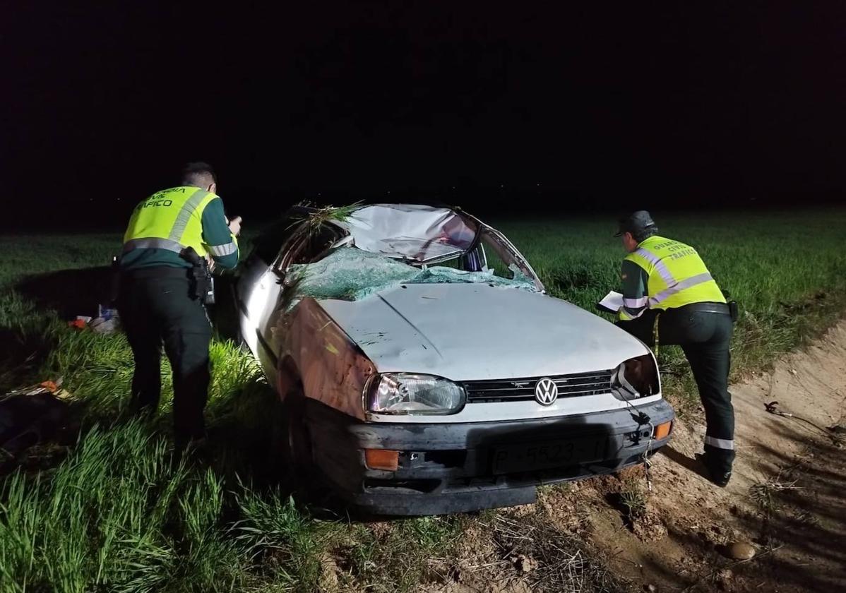 Dos agentes inspeccionan el coche siniestrado.