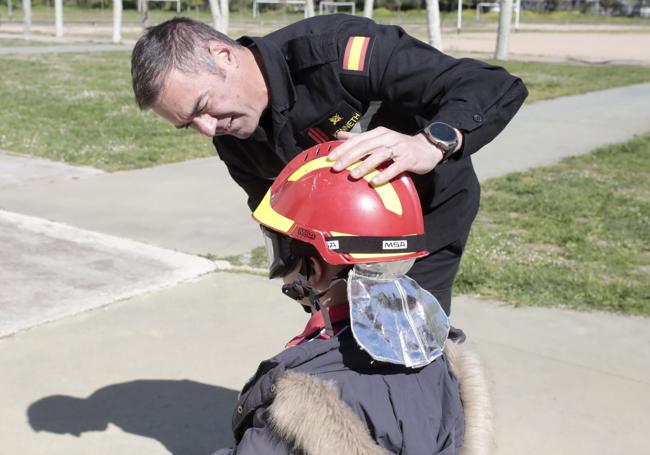 Miembro de la UME equipa con un casco a un joven alumno.