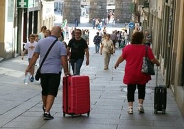 Dos personas pasean con maletas por el centro de la ciudad de Segovia.