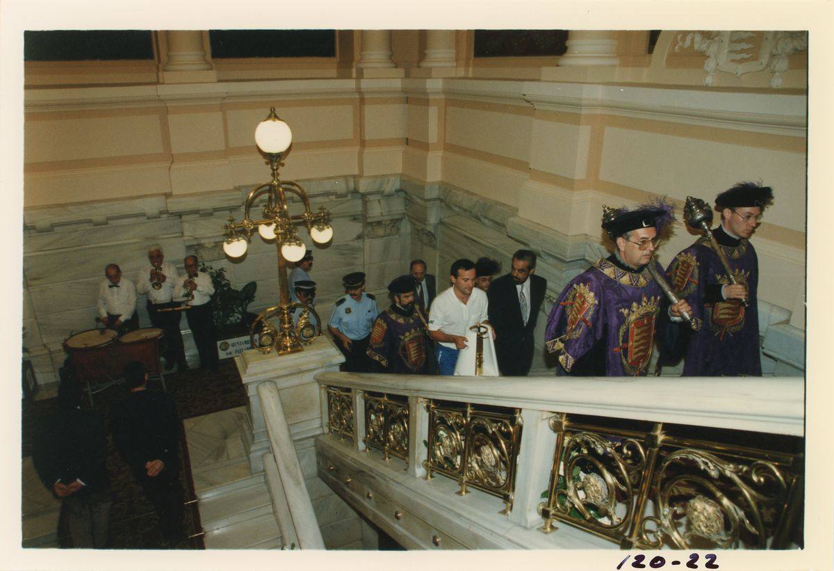 Entrada de la antorcha olímpica en el Ayuntamiento, donde pernoctó, acompañada de policías y otras autoridades, y flanqueda por los maceros. En el descansillo de la escalera, tocando, un grupo de músicos. Julio de 1992.