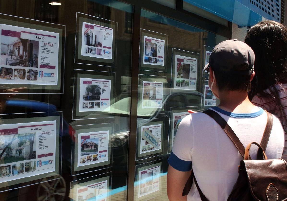 Un joven observa anuncios de viviendas en venta.