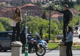 Unos turistas se toman unas fotos subidos en unos bolardos en Segovia.