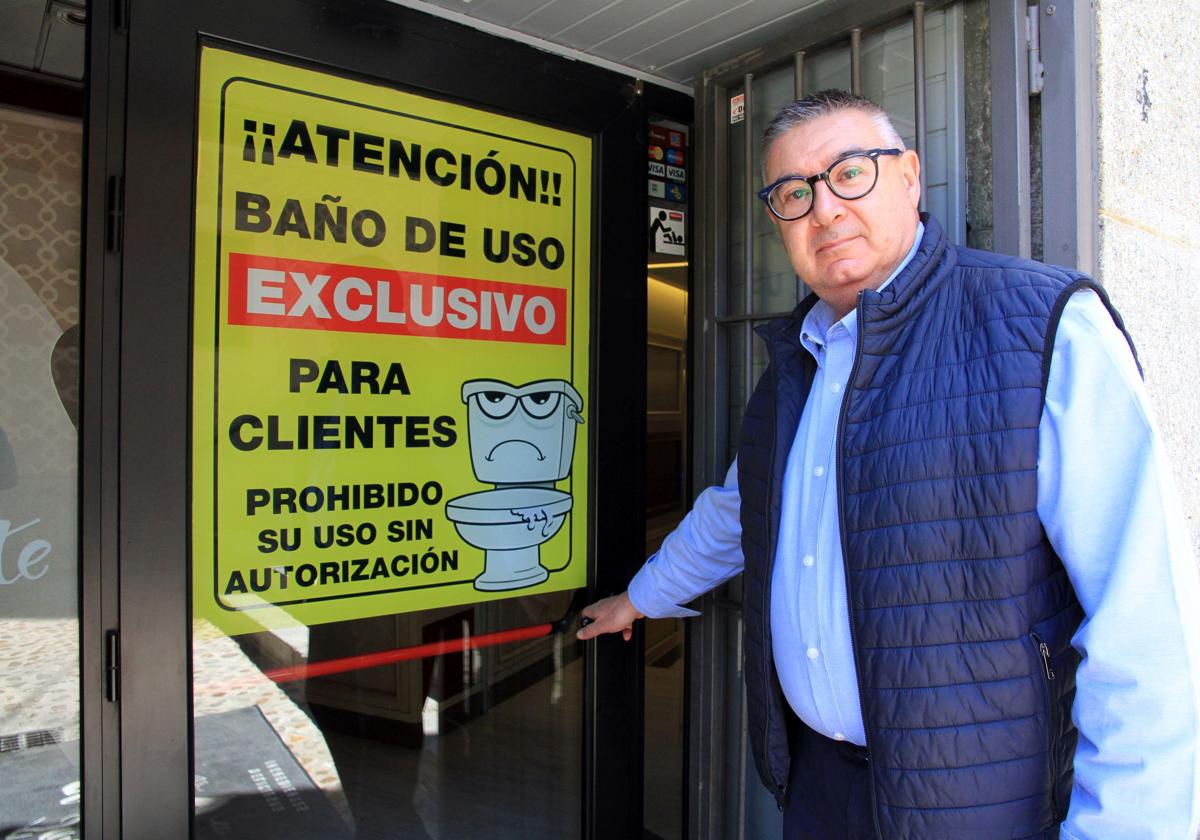 Roberto Moreno, junto a la puerta y el cartel colocado en su negocio.