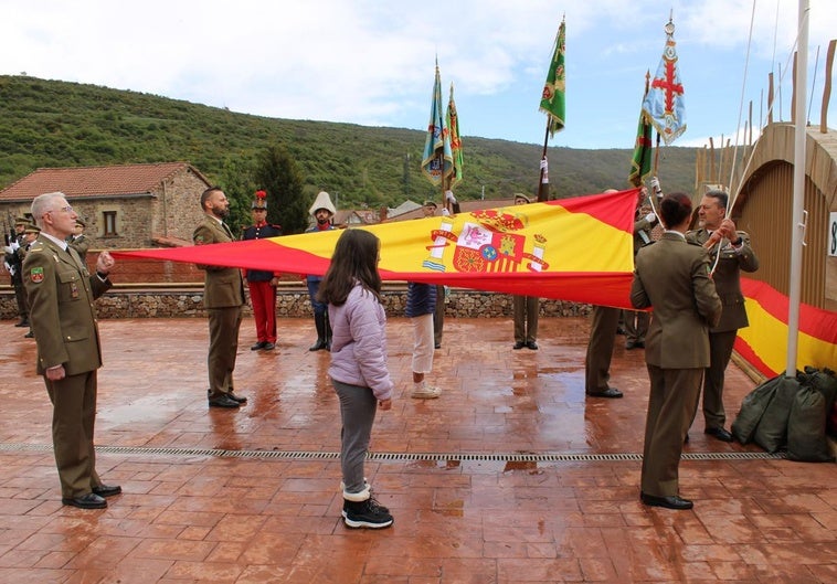 Acto castrense de izado de la bandera, con la participación de dos vecinas.