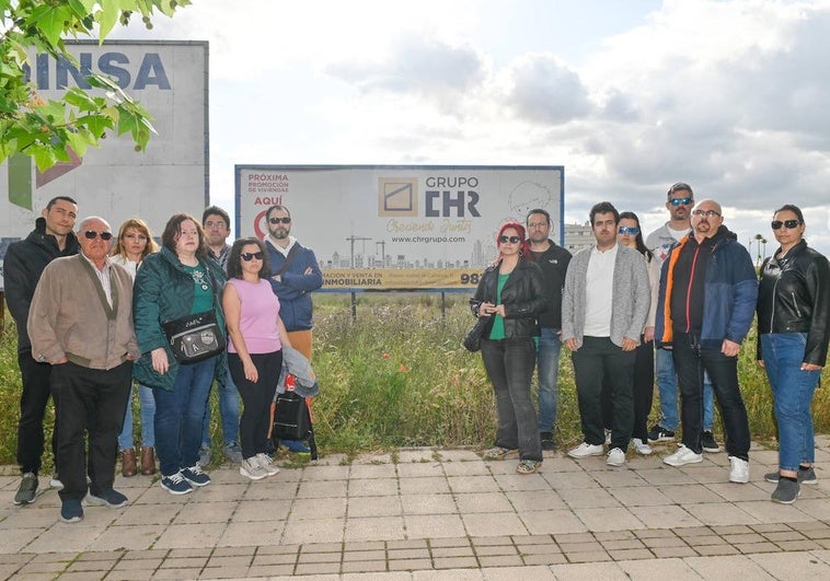 Los afectados posan junto a un cartel de la promoción situado en el solar donde estaba previsto levantar el bloque de viviendas.