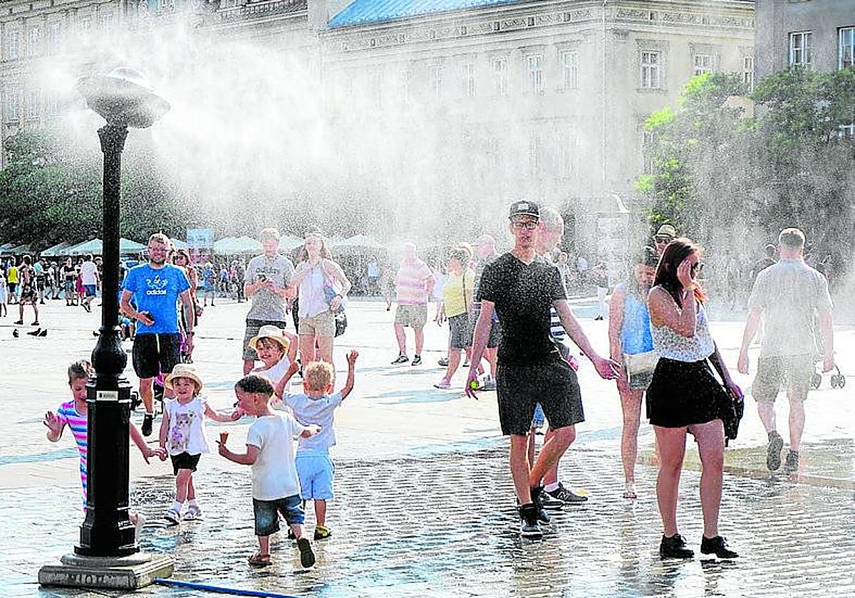 Mayores y pequeños se refrescan en un día de mucho calor.