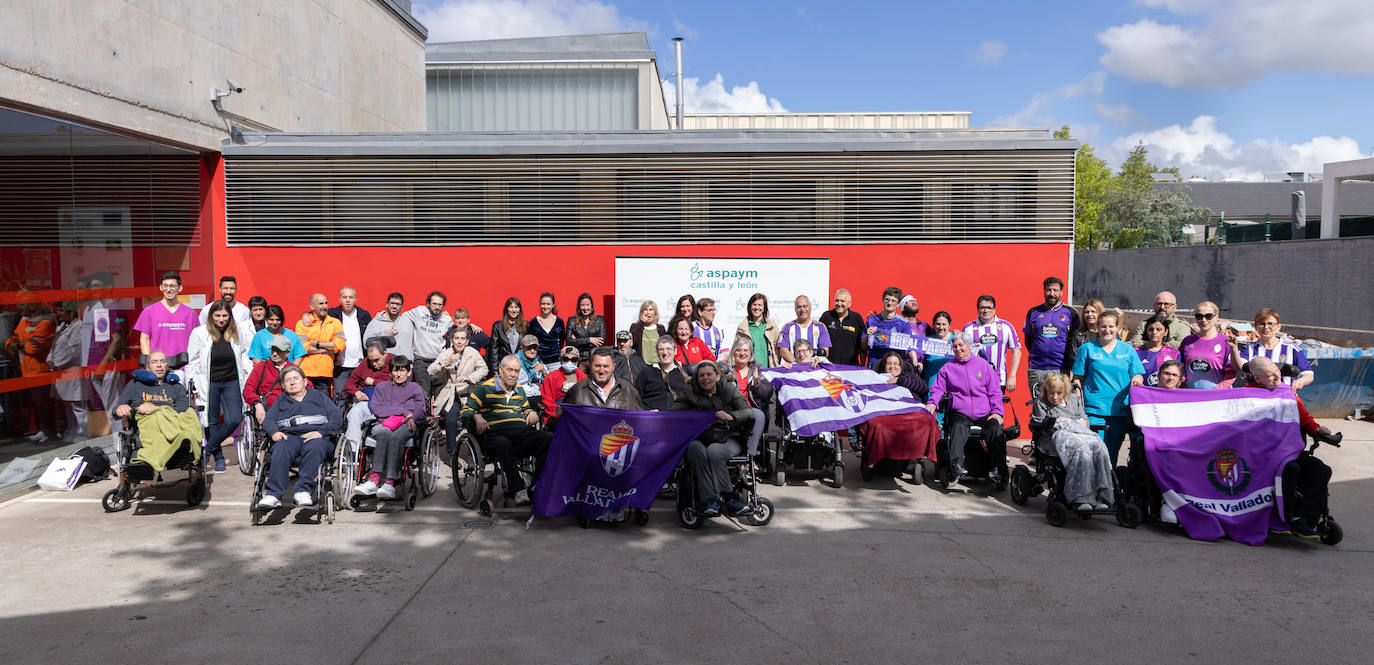 Miembros de Aspaym Castilla y León posan en las instalaciones de la asociación con banderas, camisetas y bufandas.