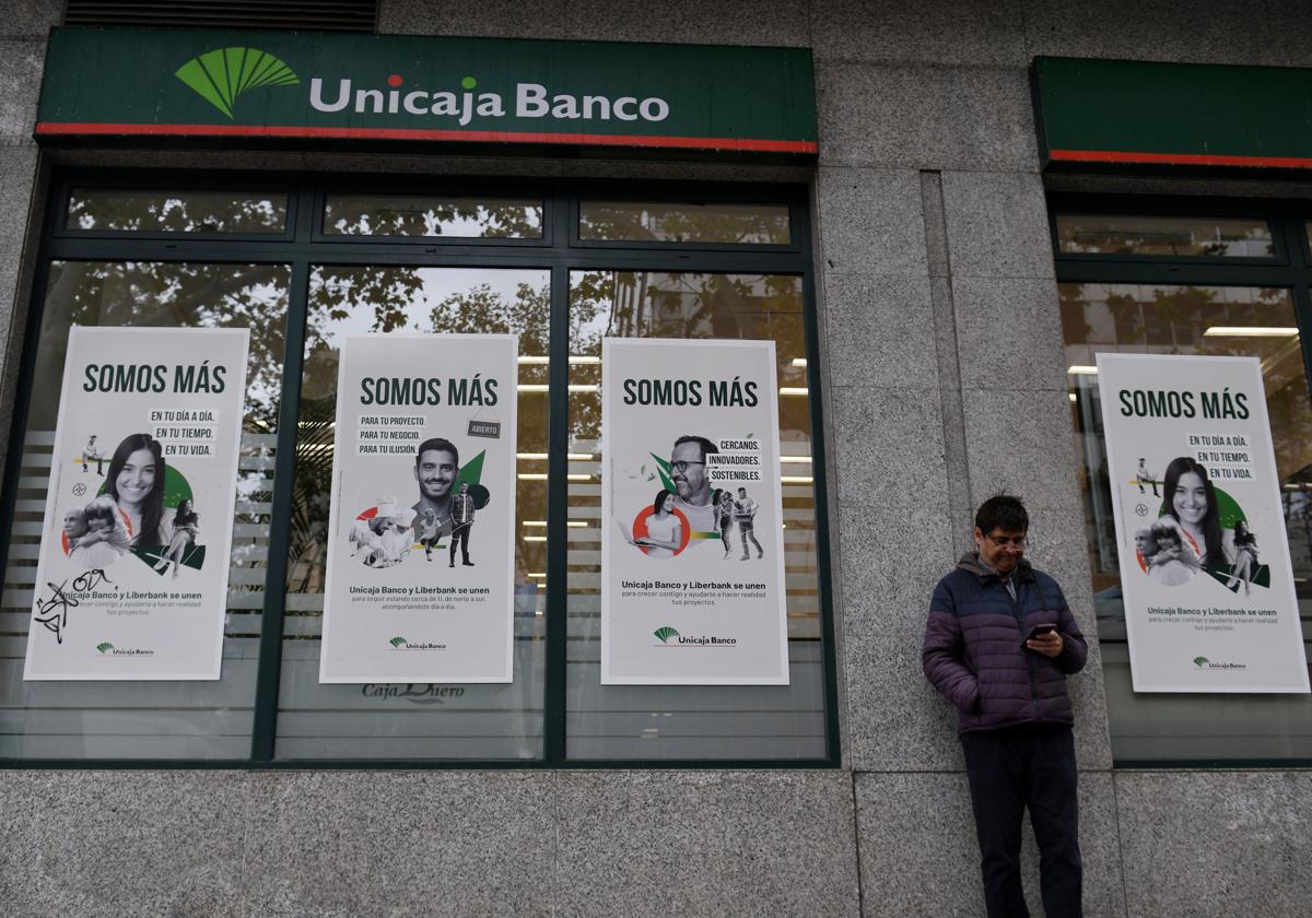 Un hombre ante una sucursal de Unicaja Banco.