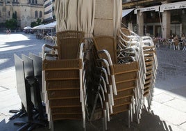 Sillas y sombrillas de una terraza apiladas en una columna de la Plaza Mayor.