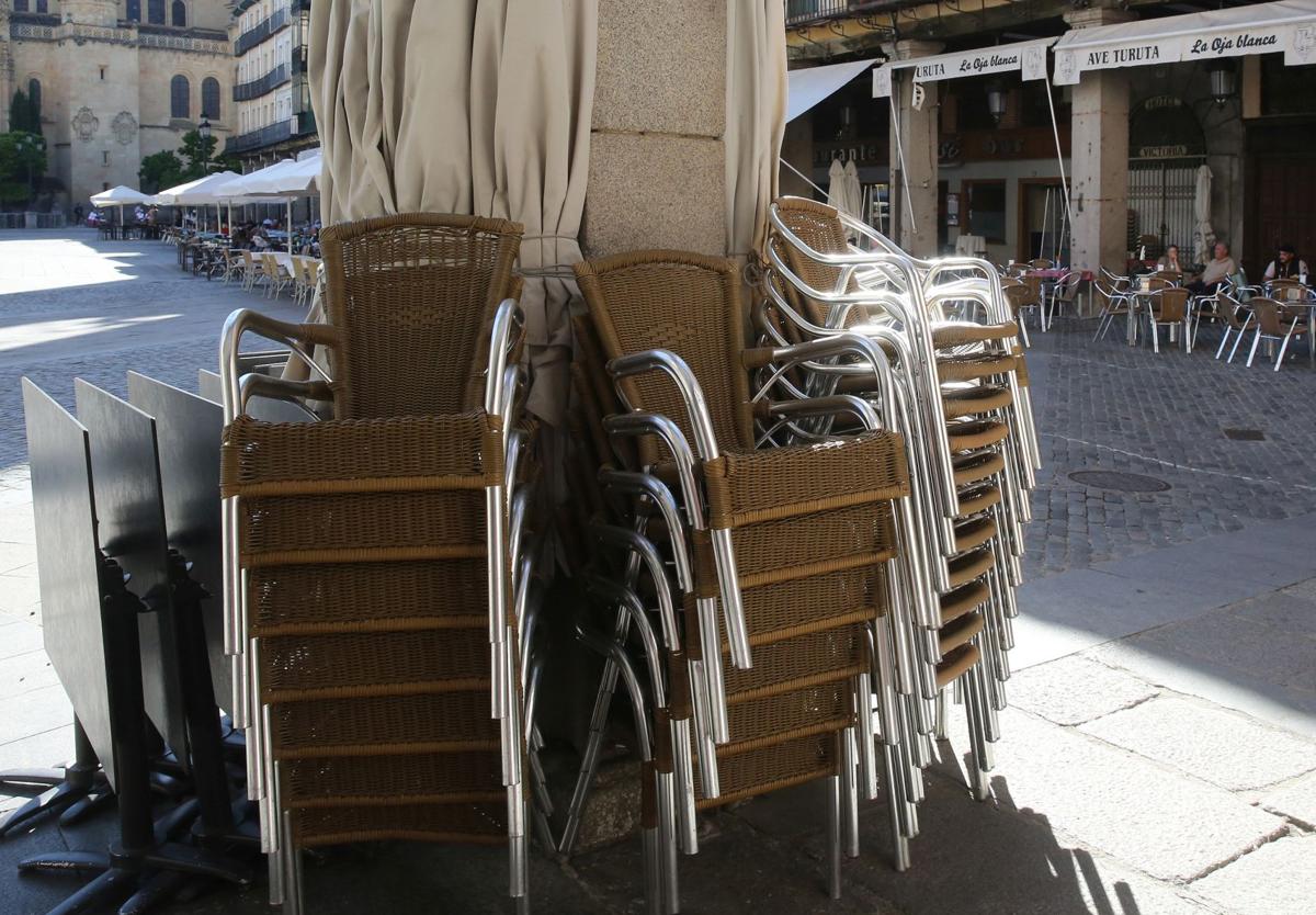 Sillas y sombrillas de una terraza apiladas en una columna de la Plaza Mayor.