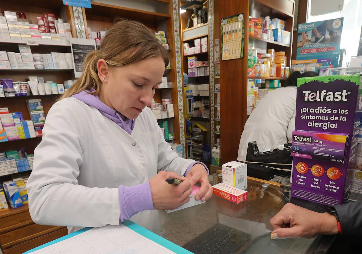 Una farmacéutica da un medicamento a un paciente en la capital palentina.