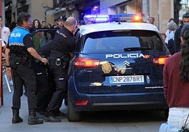 La Policía Nacional, con la colaboración de agentes locales, introducen a un detenido en la Calle Real de Segovia.