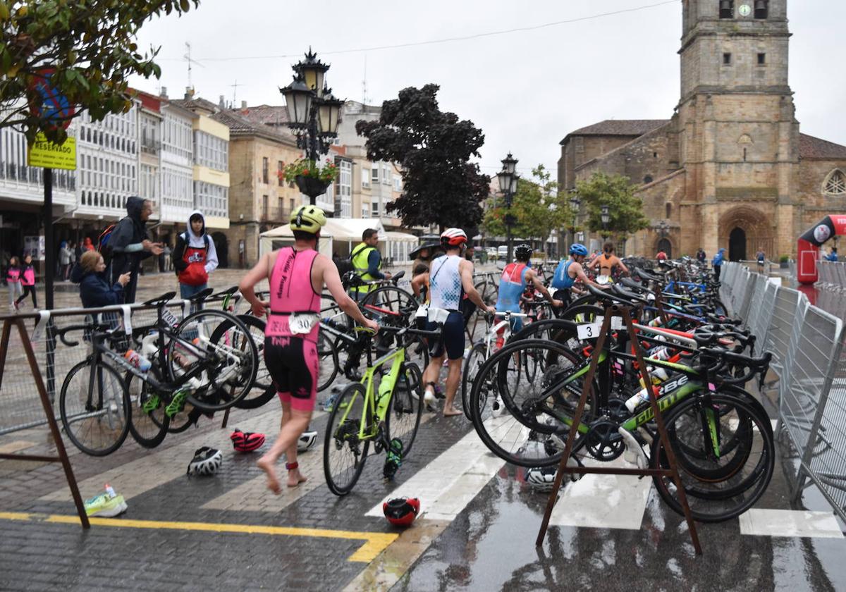 Los triatletas llegan con sus bicicletas a la Plaza de España de Aguilar para iniciar el segmento de carrera.