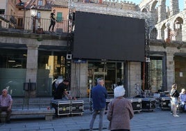 Unos transeúntes se quedan mirando la instalación de la pantalla gigante en el Azoguejo, este miércoles.