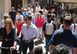 Denas de personas pasean por la Calle Real de Segovia en un día soleado.