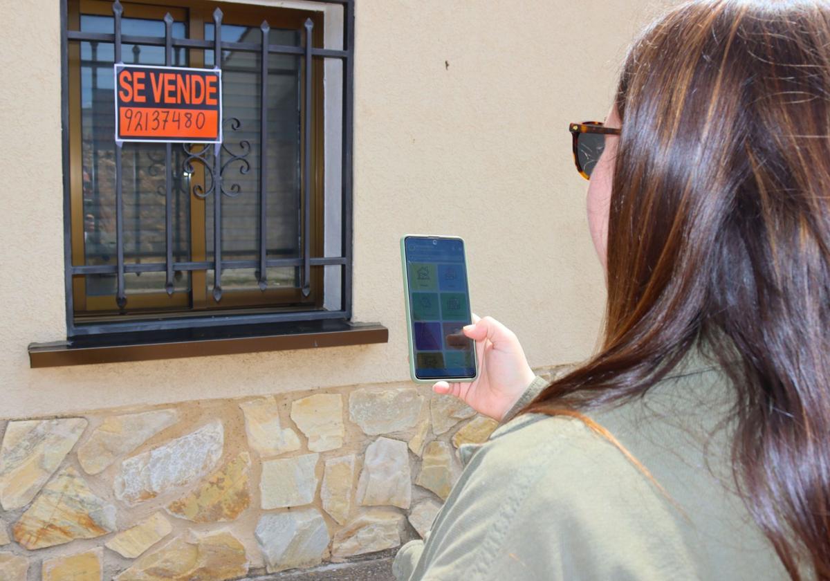 Una joven accede a la aplicación delante de una vivienda en venta en el Nordeste de Segovia.
