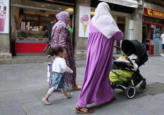 Dos mujeres pasean con una niña y un cochecito de bebé.