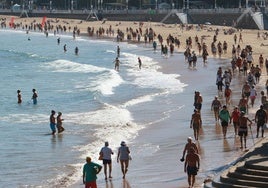 Gente paseando y tomando el sol en la playa, en imagen de archivo.