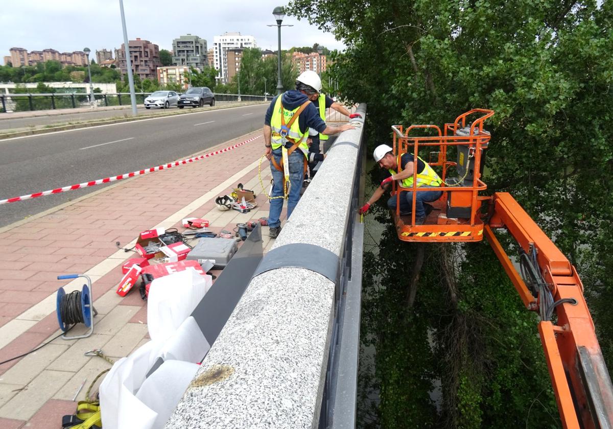 Los operarios colocan las últimas chapas en el canto del puente de Juan de Austria.