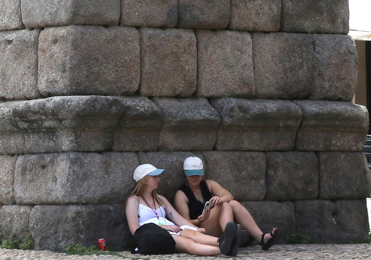 Dos turistas se refugian de la radiación bajo los arcos del Acueducto de Segovia, este jueves.