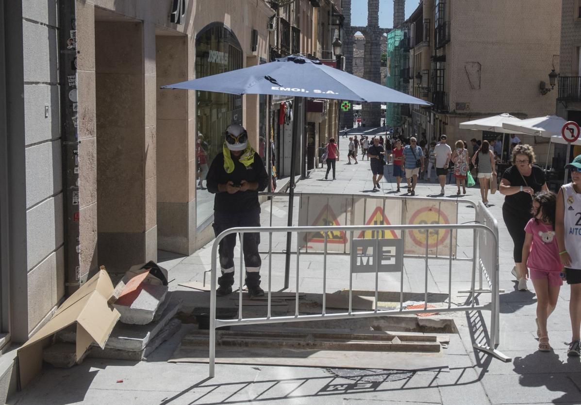 Un trabajador se protege del sol con una sombrilla en la Calle Real de Segovia, este martes.