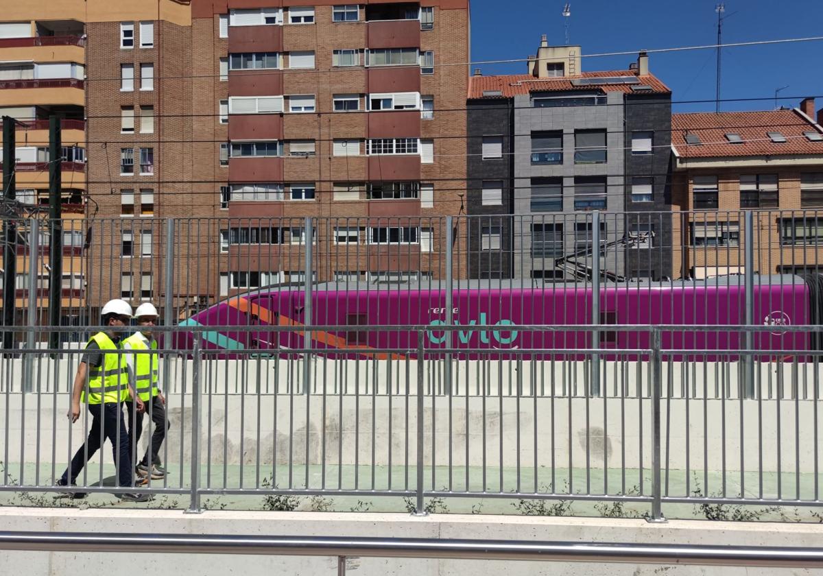 El concejal y uno de los técnicos de las obras recorren el carril bici pegado a la valla, en la calle Guipuzcoa, mientras pasa un Avlo.