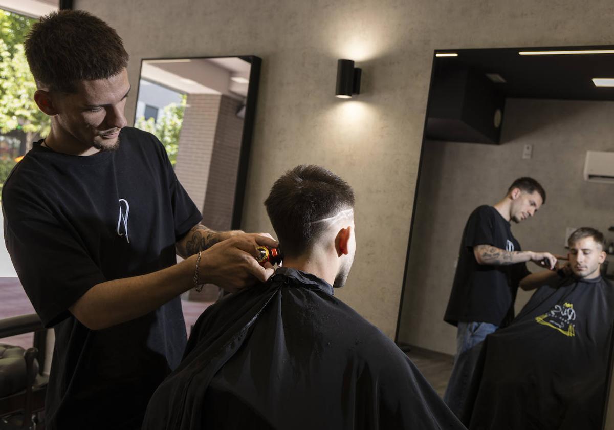 El barbero Carlos Yllera corta el pelo a un cliente.