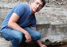 Carlos Calvo, alcalde de Carbonero de Ahusín, mete la mano en el agua del manantial.