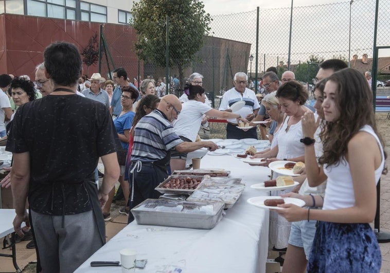 Decenas de personas recogen su ración de huevos fritos con chorizo en Torrecaballeros.