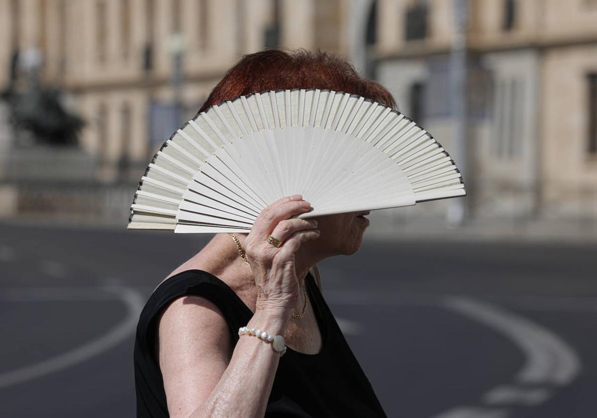 Una mujer intenta tapar el sol con un abanico, en la plaza de Zorrilla de Valladolid.