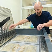 Mario Moreno sumerge dos hojas en una solución para restituir las pérdidas de papel.