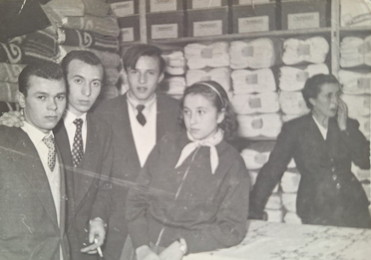 Imagen principal - Arriba, Ángel Sánchez con sus hermanos y su madre en los almacenes de la familia, en la calle Santiago. Abajo, llegada del féretro el 21 de agosto de 1959 y el piragüista en la playa con un primo suyo.