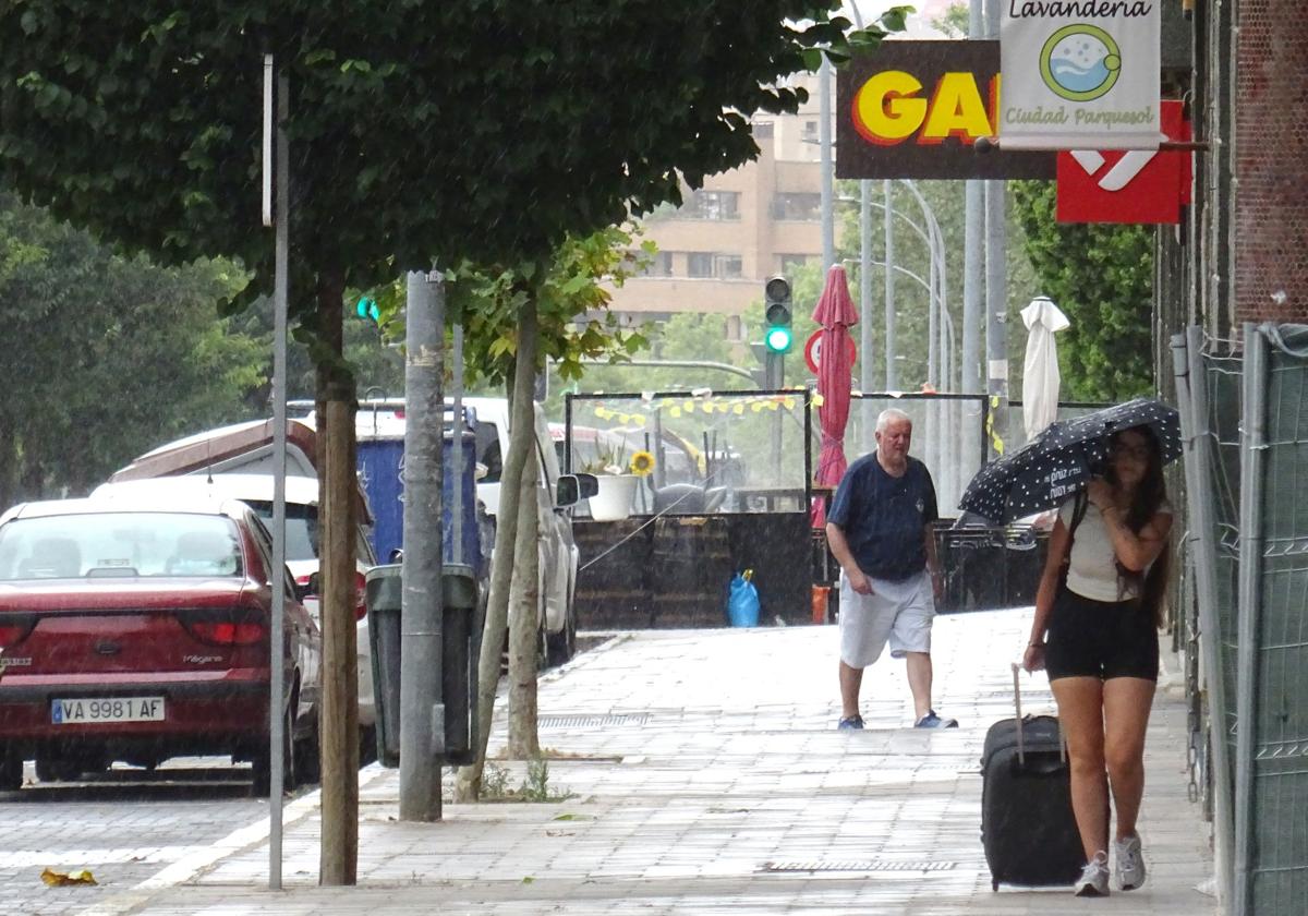 Dos vecinos de Parquesol se protegen de la lluvia, este verano.