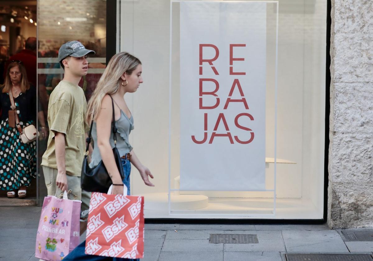 Una pareja de jóvenes con bolsas en la calle Santiago de Valladolid al inicio de las rebajas de verano de este año.