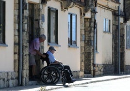 Un hombre asiste a una persona mayor en silla de ruedas en la provincia de Segovia.